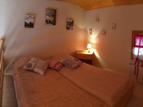 une chambre avec un lit avec deux oreillers dessus dans l'établissement Charmant studio 2ème étage, balcon sud, à deux pas télésiège et commerces, calmes et ensoleillé - FR-1-416-180, à La Toussuire