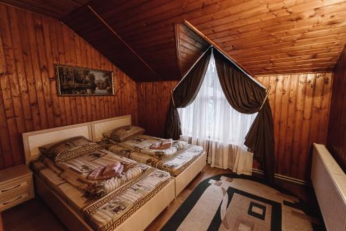 two beds in a wooden room with a window at Toga cottage in Yablunytsya