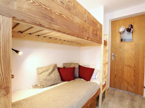 Cette chambre comprend un lit superposé avec des oreillers rouges. dans l'établissement Appartement skis aux pieds pour 4 pers - Courchevel Village - FR-1-575-10, à Courchevel
