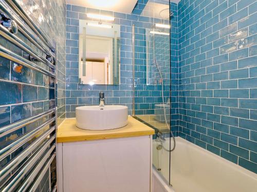 une salle de bain carrelée bleue avec un lavabo et une baignoire dans l'établissement Appartement skis aux pieds pour 4 pers - Courchevel Village - FR-1-575-10, à Courchevel