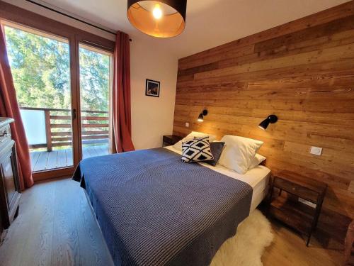 ein Schlafzimmer mit einem Bett mit einer Holzwand in der Unterkunft Appartement lumineux 4 pièces aux Gets, accès direct aux pistes, 6 pers, garage, Wi-Fi - FR-1-598-37 in Les Gets