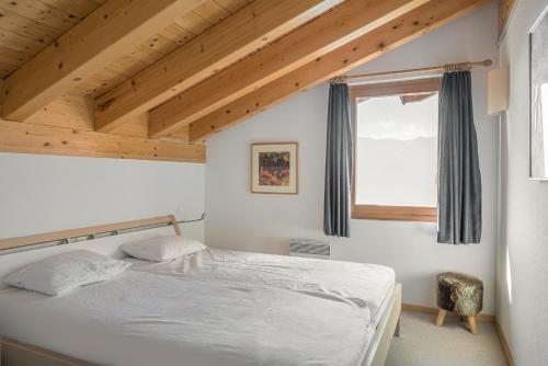 a bedroom with a white bed and a window at Camelot 5 in Bettmeralp