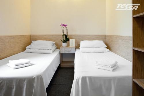 two beds in a room with white sheets and towels at Pokoje Gościnne Tessa in Chełm