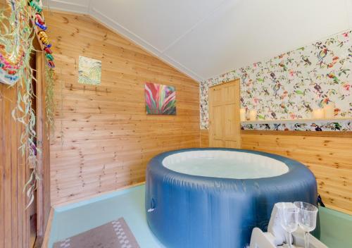 uma grande banheira azul num quarto com paredes de madeira em Little Ponds em Cross in Hand