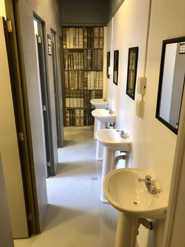 a row of sinks in a bathroom with a row of toilets at ROOMIES HOSTEL Parque México in Mexico City