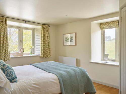 Yennadon Cottage في توتنس: غرفة نوم بها سرير ونافذتين