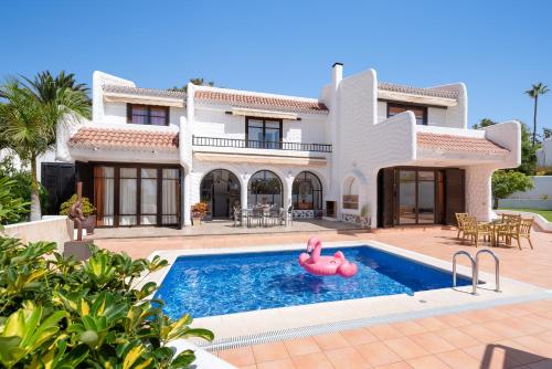 a villa with a swimming pool in front of a house at KARAT Villa Atlantida in Playa de las Americas