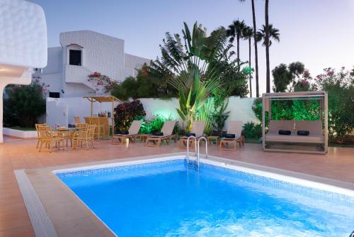 a swimming pool with a patio and a table and chairs at KARAT Villa Atlantida in Playa de las Americas