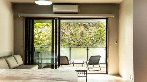a bedroom with a bed and a balcony with chairs at Rakuten STAY MOTEL Nikko Kinugawa Dog Friendly Room in Nikko