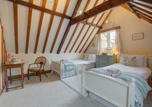 a bedroom with two beds and a desk at Camberley Cottage in Happisburgh