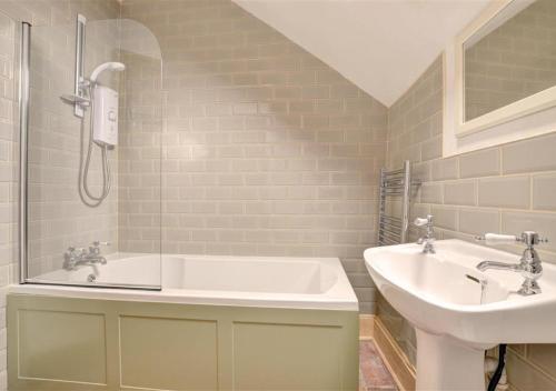 a bathroom with a sink and a tub and a toilet at Poppy Cottage in Bodham