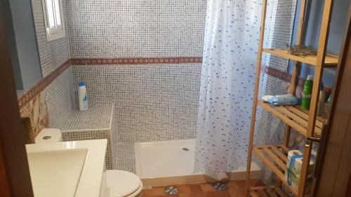 y baño con cortina de ducha y aseo. en Casa Rústica vacacional FILIGRANA en Sanlúcar de Barrameda Zona Montijo, en Chipiona
