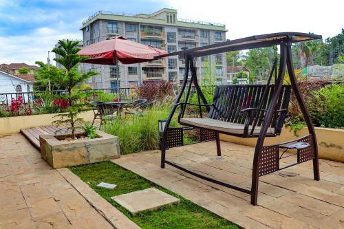 a swing with an umbrella on a patio at Welcome to Taria. A cosy new studio apartment in Nairobi