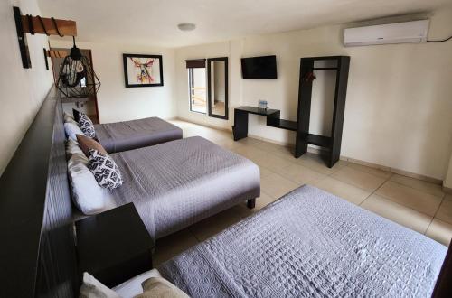 Sala de estar con 2 camas y TV en Hotel Sierra Linda en Xilitla
