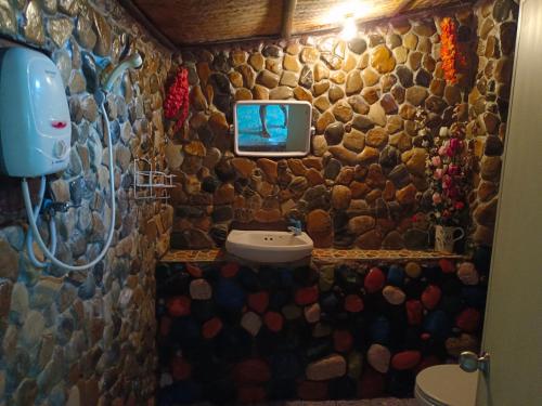 ein Bad aus Stein mit einem Waschbecken und einem TV an der Wand in der Unterkunft sunny Tayai hostel pai in Pai
