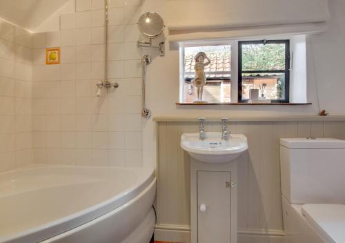 a bathroom with a sink and a tub and a toilet at Apple Tree Cottage in Poringland