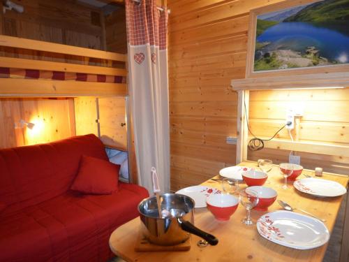 ein Wohnzimmer mit einem Tisch und einem roten Sofa in der Unterkunft Studio Les Menuires, 1 pièce, 2 personnes - FR-1-452-283 in Les Menuires