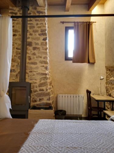 a bedroom with a bed and a fireplace and a table at Casa rural El Forn d'Alcudia de Veo in Alcudia de Veo