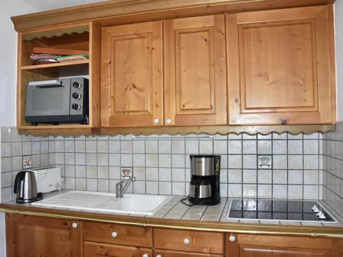 un comptoir de cuisine avec un évier et un micro-ondes dans l'établissement Appartement 3 pièces avec terrasse, parking et accès pistes – Pralognan - FR-1-464-190, à Pralognan-la-Vanoise
