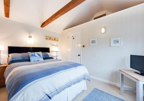 a bedroom with a large bed and a television at Little Rosa in Wells next the Sea