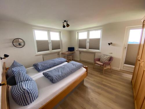 sypialnia z łóżkiem z niebiesko-białymi poduszkami w obiekcie Pension Hilde w mieście Sulzberg
