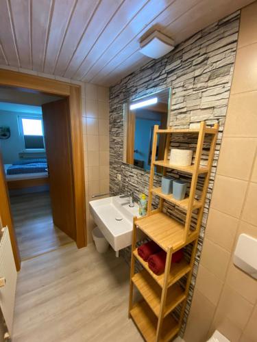 a bathroom with a sink and a stone wall at Pension Hilde in Sulzberg