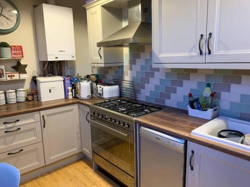 a kitchen with white cabinets and a stove top oven at Bright and Cosy 2 bedroom flat, close to station in Sydenham
