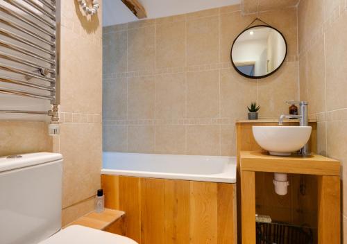 W łazience znajduje się umywalka, toaleta i lustro. w obiekcie Star Cottage w mieście Holt