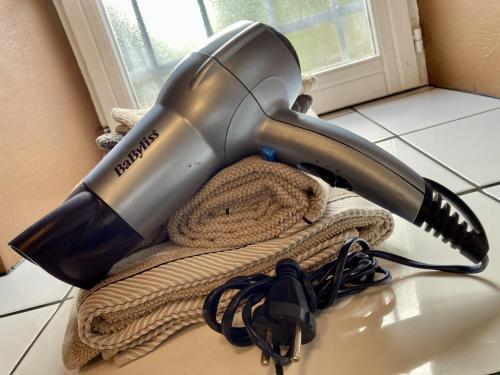 a blow dryer sitting on top of a towel at AUX 4 LOGIS Appart-hotel - Studio Le City - Petit déjeuner inclus 1ère nuit in Foix