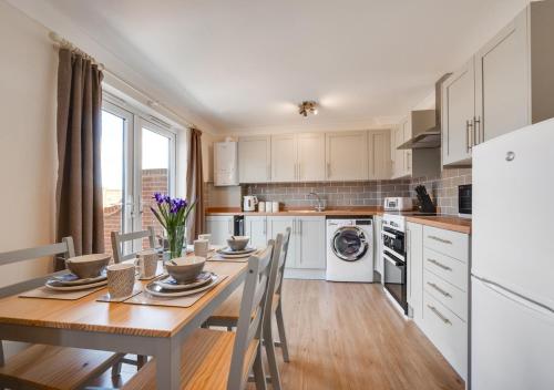 a kitchen with a wooden table with chairs and a dining room at The Cart Lodge in Chedgrave
