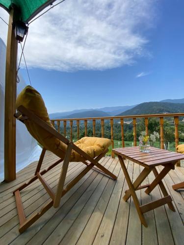 a rocking chair and a table on a deck at DENGEKORU Wildlife & Glamping in Mudurnu