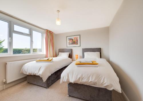 two beds in a room with two windows at Journeys End in Ringstead