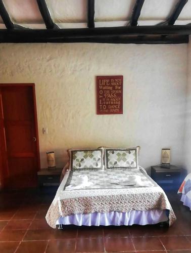 a bedroom with a bed with two night stands and a sign on the wall at Hotel Campestre Franchesca in Tabio