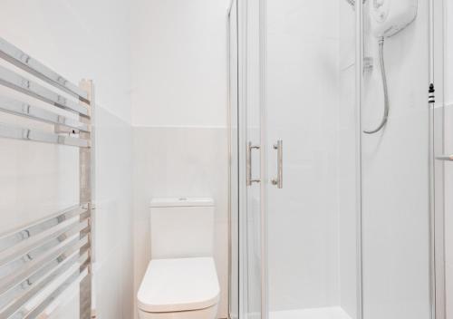 a white bathroom with a toilet and a shower at Eva Cottage in West Runton