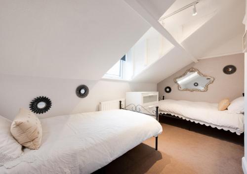 a attic bedroom with two beds and a mirror at Eva Cottage in West Runton