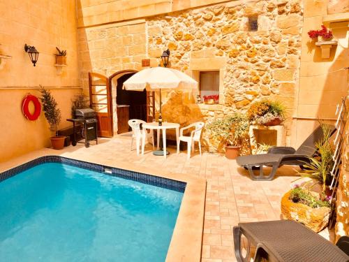 a swimming pool in a yard with a table and chairs at Brooklyn Farmhouse in Żebbuġ
