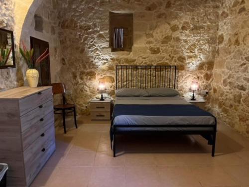 um quarto com uma cama e uma parede de pedra em Brooklyn Farmhouse em Żebbuġ