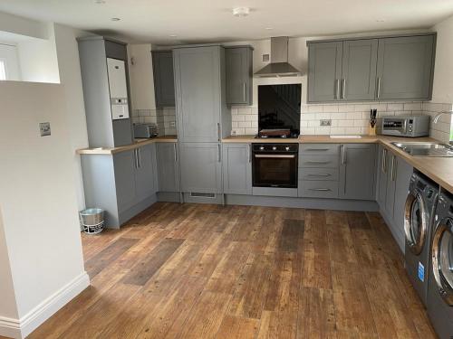 a kitchen with gray cabinets and a wooden floor at Connah's Quay Park Farm Barns in Connahs Quay