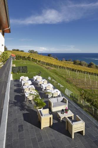 a row of white tables and benches on a patio at Hotel San Prudentzio in Getaria