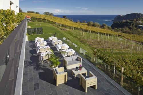 a row of white tables and chairs in a vineyard at Hotel San Prudentzio in Getaria