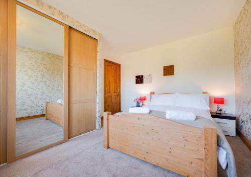 a bedroom with a bed and a large mirror at Skippers Retreat in Dersingham