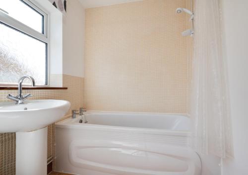 y baño con lavamanos, bañera y lavamanos. en Skippers Retreat, en Dersingham