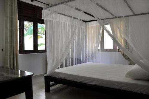 希卡杜瓦的住宿－Harris Villa，一间卧室配有一张带天蓬的床