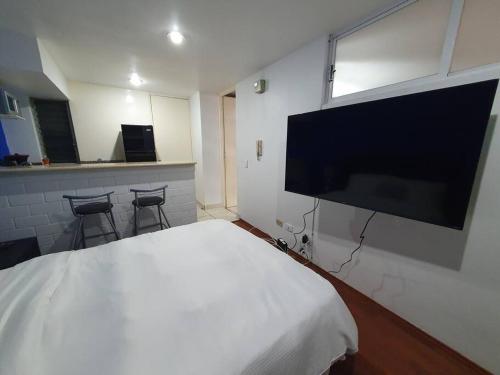 1 dormitorio con 1 cama blanca y TV de pantalla plana en Super Suite con baño y cocina excelente ubicación, en Ciudad de México