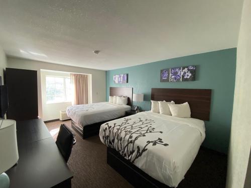 a hotel room with two beds and a desk at Sleep Inn Jacksonville Airport in Jacksonville