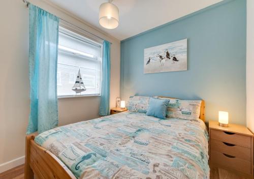 Un dormitorio con una cama con paredes azules y una ventana en Smugglers Top, en Walcott