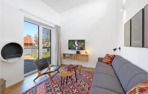 a living room with a gray couch and a tv at Nice Home In Lembruchdümmer See in Lembruch