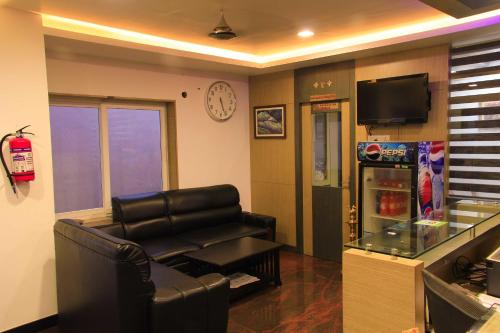 a living room with a leather couch and a tv at Hotel Sri Hayagriva in Srīrangam