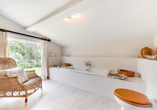 a bathroom with a tub and a chair and a sink at Dilham House in Dilham