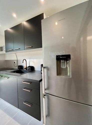 a kitchen with a stainless steel refrigerator and a sink at Coconut Room - Entre mer et forêt avec piscine in Rémire-Camp